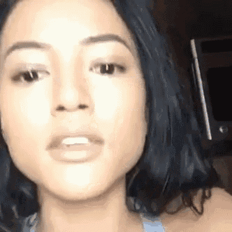 a close up of a woman 's face with her mouth open and a phone in the background .