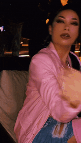 a woman in a pink jacket is sitting on a white couch