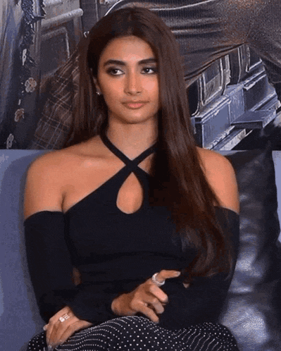 a woman is sitting on a couch wearing a black top and polka dot pants