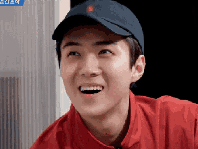 a young man wearing a black hat and a red shirt smiles