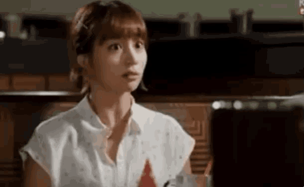 a woman in a white shirt is sitting at a table in a restaurant .