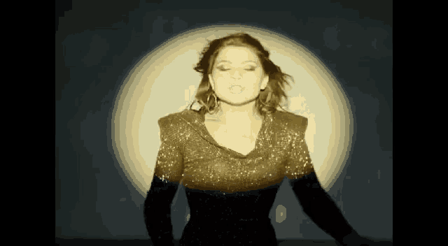 a woman in a black dress is standing in front of a large light .