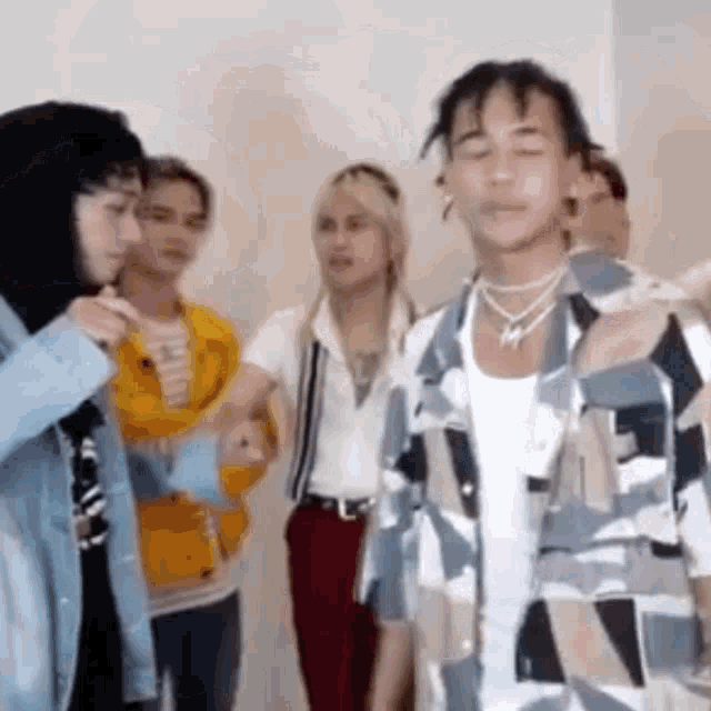 a group of people are standing next to each other in a room and talking to each other .