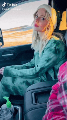 a woman in a green tie dye outfit is sitting in the back seat of a car with a tiktok watermark