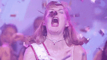 a woman is screaming in front of a crowd of people at a party .