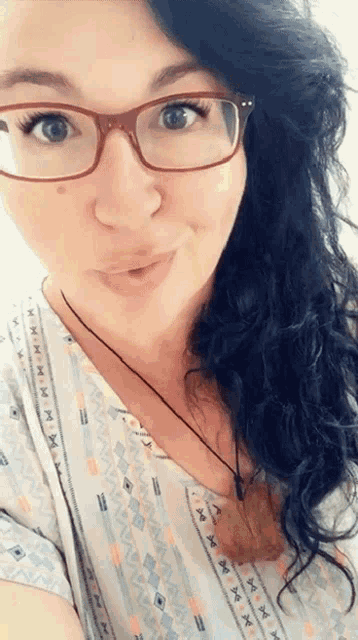 a woman wearing glasses and a shirt with a pattern that says x on it