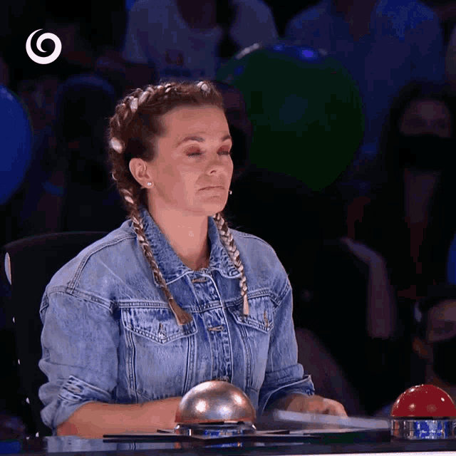 a woman in a denim jacket sits at a desk with a ring on it