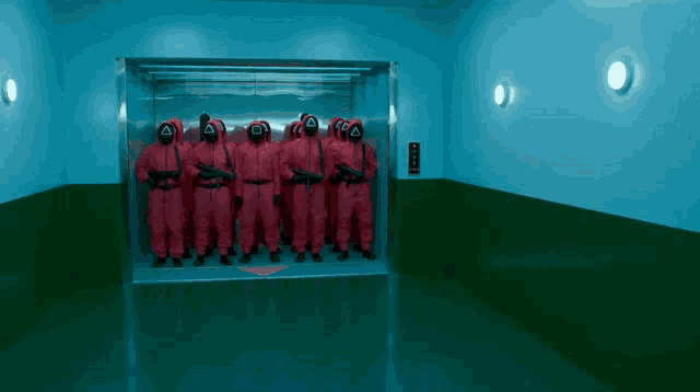 a group of people in red jumpsuits and masks with the letter l on their faces