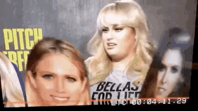 a group of women are standing next to each other in front of a sign that says pitch perfect