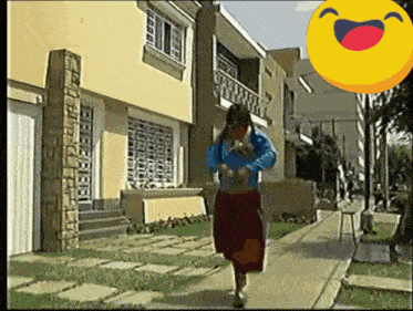 a woman is walking down a sidewalk in front of a building with a smiley face in the background