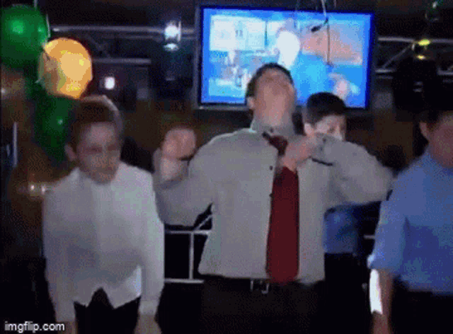 a group of people are dancing in a room with balloons and a television .