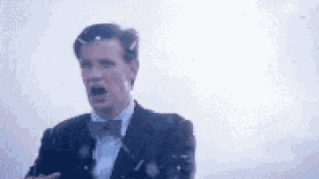a man in a suit and bow tie is standing in front of a white background .