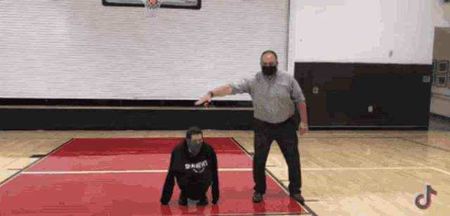 a man wearing a mask stands next to a man wearing a black sweatshirt that says eagles on it