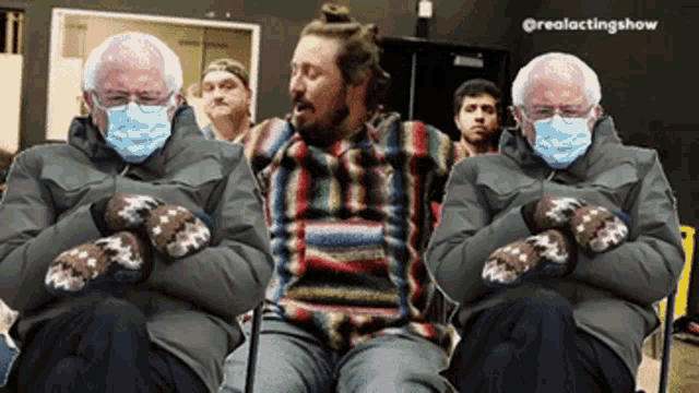 two men wearing face masks and mittens are sitting next to each other in a room