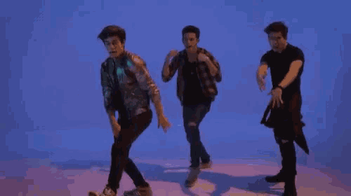 a group of young men are dancing together in a blue room .