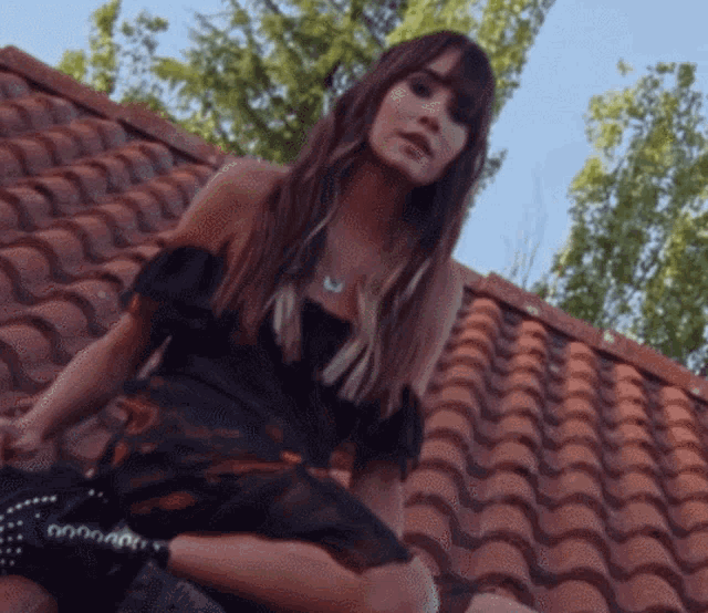 a woman in a black dress sits on a roof