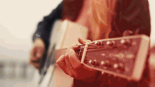 a person is playing an acoustic guitar with a red background