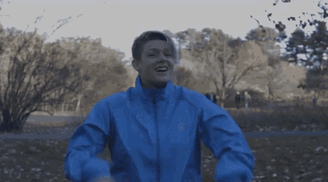 a person wearing a blue jacket with the word asics on the front