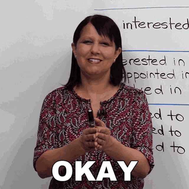 a woman holding a pen in front of a white board that says interested