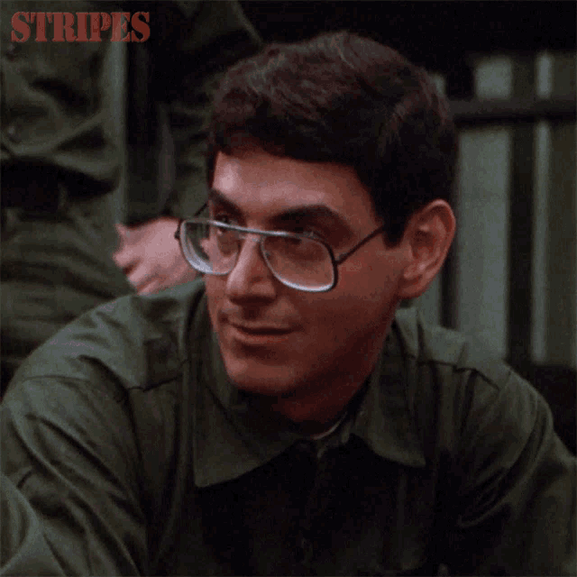 a man wearing glasses and a green shirt with the words stripes on the bottom right