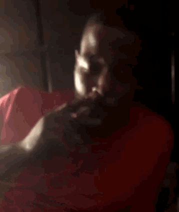 a man in a red shirt is looking down with his eyes closed