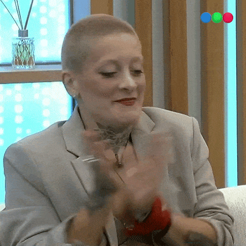 a woman with a shaved head is sitting on a couch with her arms outstretched