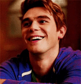 a young man in a blue hoodie is smiling .