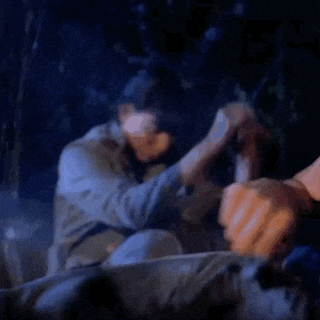 a blurry picture of a man holding another man 's hand in a dark room at night .