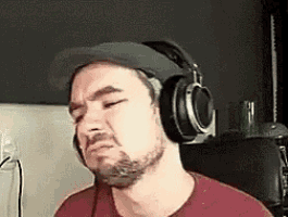 a man with a beard wearing headphones and a hat is making a face .