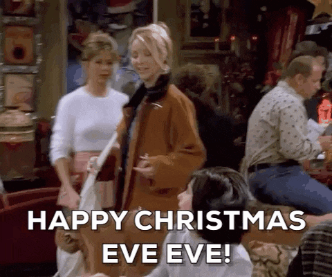 a group of people are standing in a room and one of them is saying happy christmas eve eve !