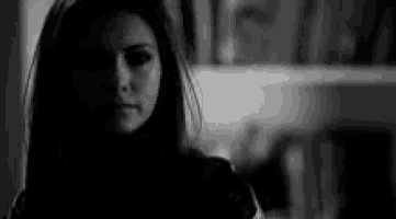 a black and white photo of a woman in a dark room .