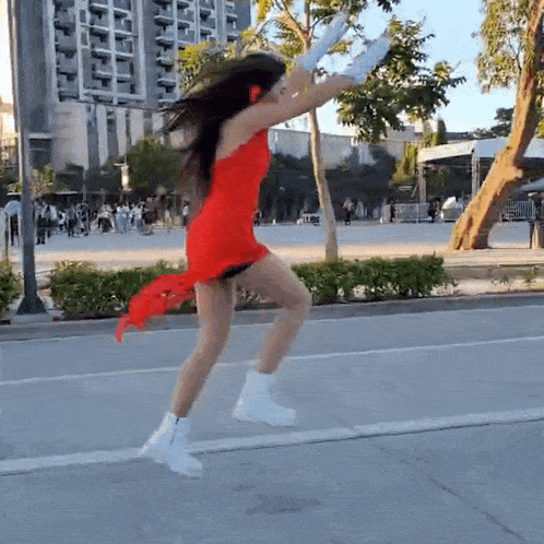 a woman in a red dress and white boots is running down a street .