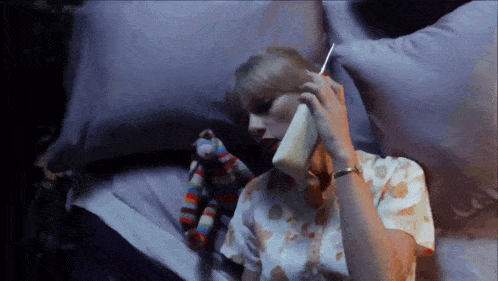a woman laying on a bed talking on a phone