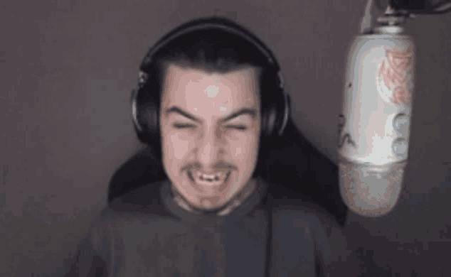 a man wearing headphones is making a funny face in front of a white microphone