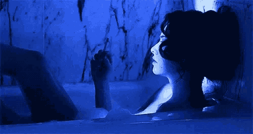 a woman is taking a bath in a bathtub in a dark room .