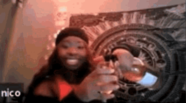a woman is holding a glass of wine and smiling in front of a painting .