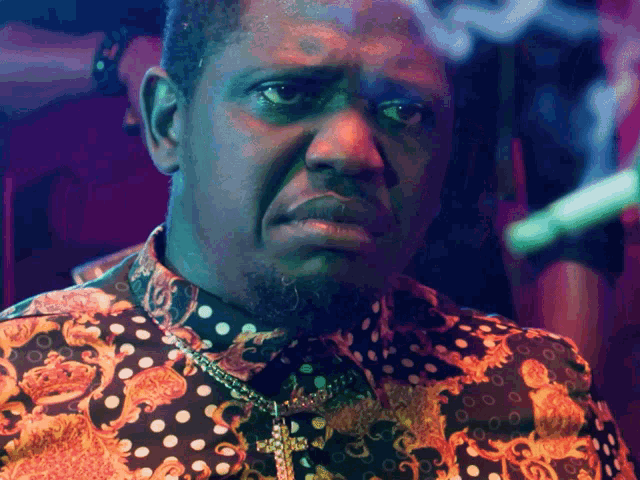 a man is wearing a polka dot shirt and a cross necklace