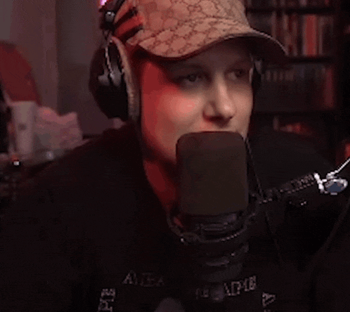 a man wearing headphones and a hat is talking into a microphone