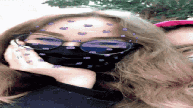 a woman wearing glasses and a mask with purple dots on her forehead