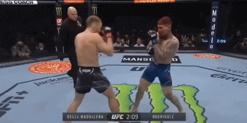 two men are fighting in a boxing ring with a monster logo on the ground .
