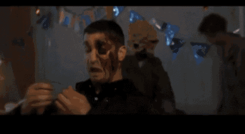 a man with blood on his face is standing in a room with balloons