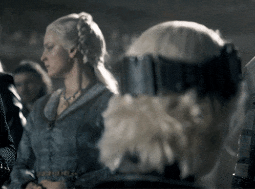 a woman in a blue dress is standing next to a man in armor