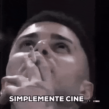 a man is covering his mouth with his hands while watching a movie at the cinema .