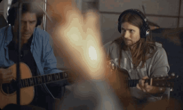 a man wearing headphones is playing a guitar with the letter n on the neck