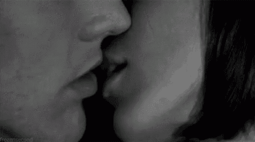 a black and white photo of a man and a woman kissing .