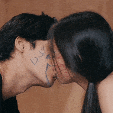 a man and a woman are kissing with a drawing of a heart on the man 's face