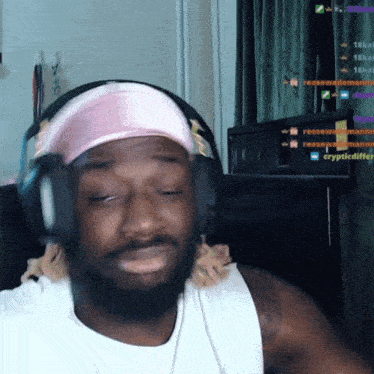 a man wearing headphones and a pink headband is sitting in front of a computer screen that says crypticdiffer