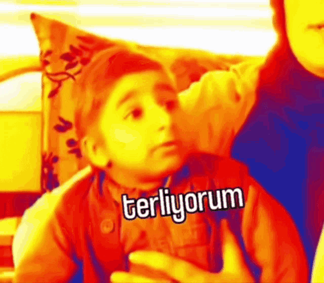 a little boy is sitting on a couch with the word terliyorum written on his shirt