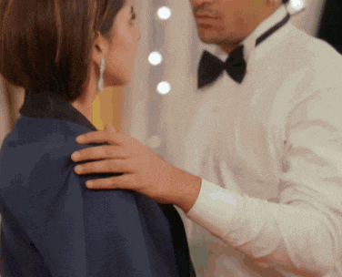 a man in a tuxedo is touching the shoulder of a woman