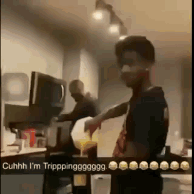 a man is pouring orange juice into a pitcher in a kitchen while another man looks on .